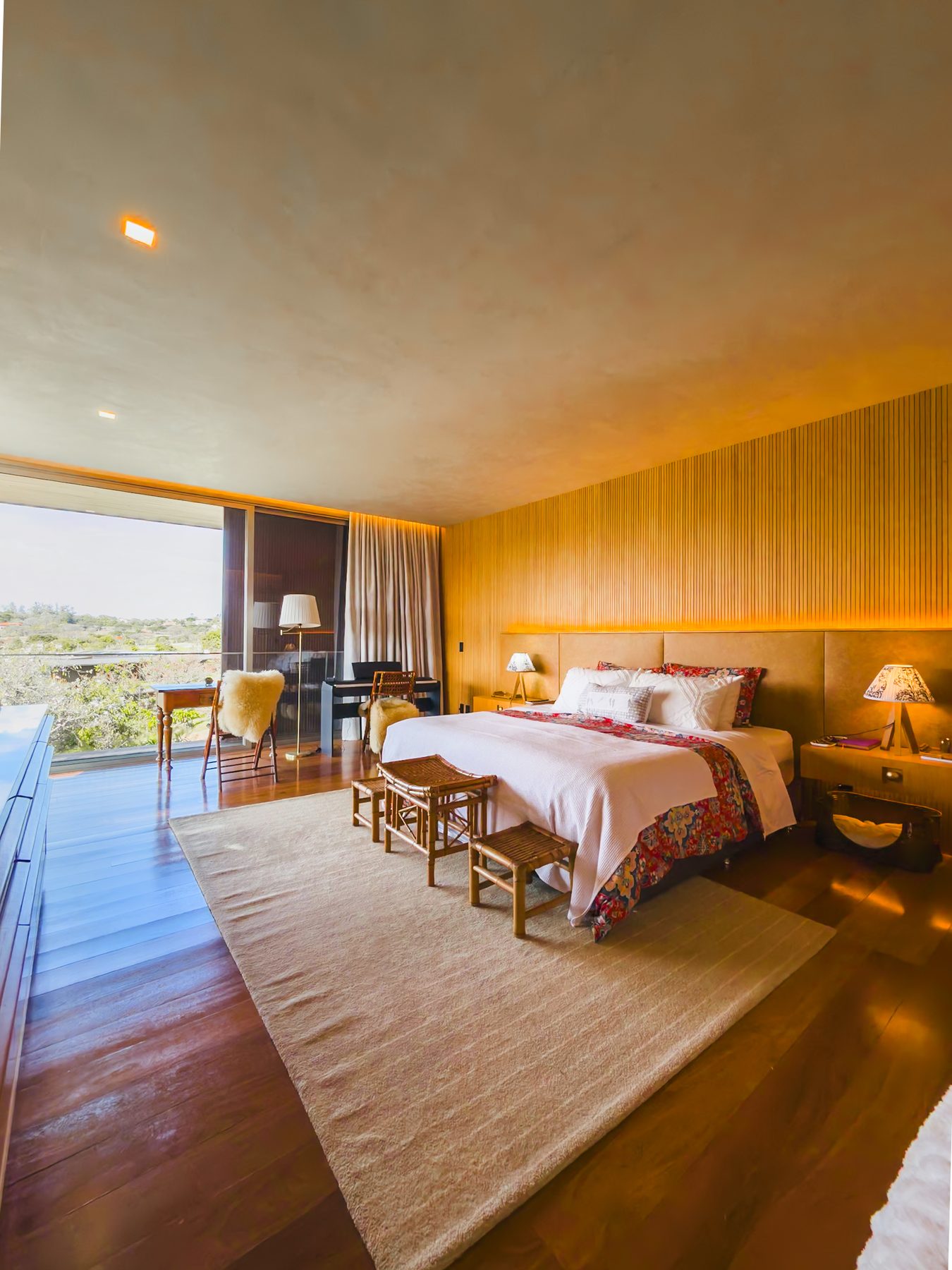 Suíte master com cama de casal, tapete claro e janela ampla para a paisagem