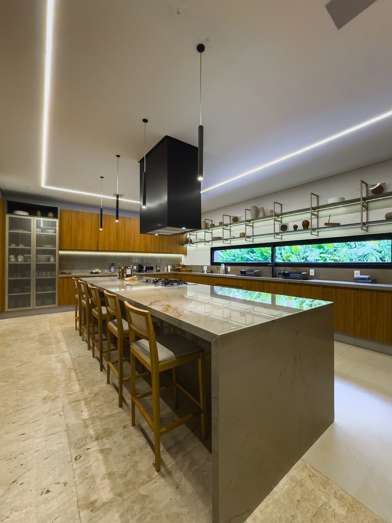 Cozinha com ilha, banquetas de madeira e prateleiras sob forro claro com iluminação embutida