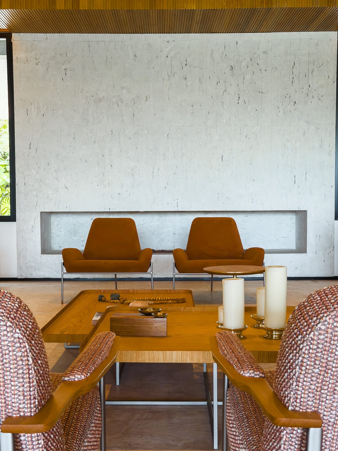 Estar com poltronas de couro e mesa de centro diante da lareira embutida na parede de pedra