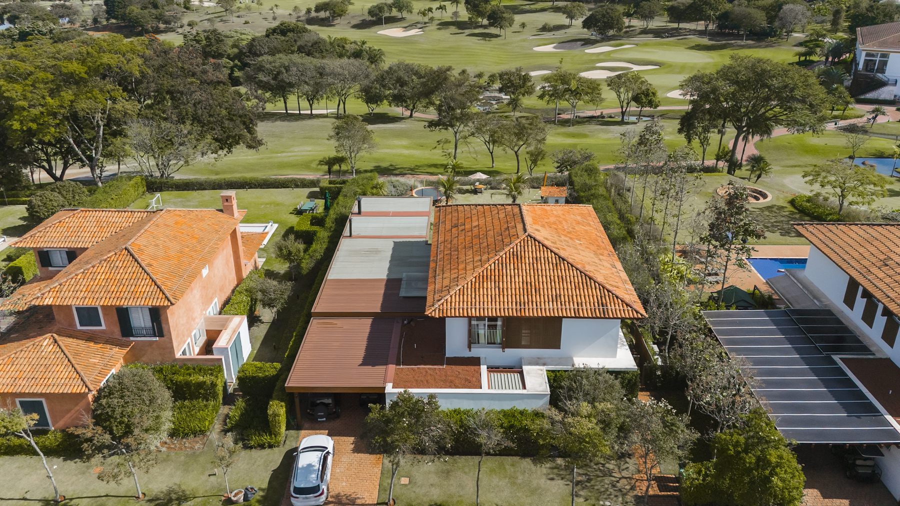 Vista aérea da casa de telhado cerâmico, com o campo de golfe logo atrás