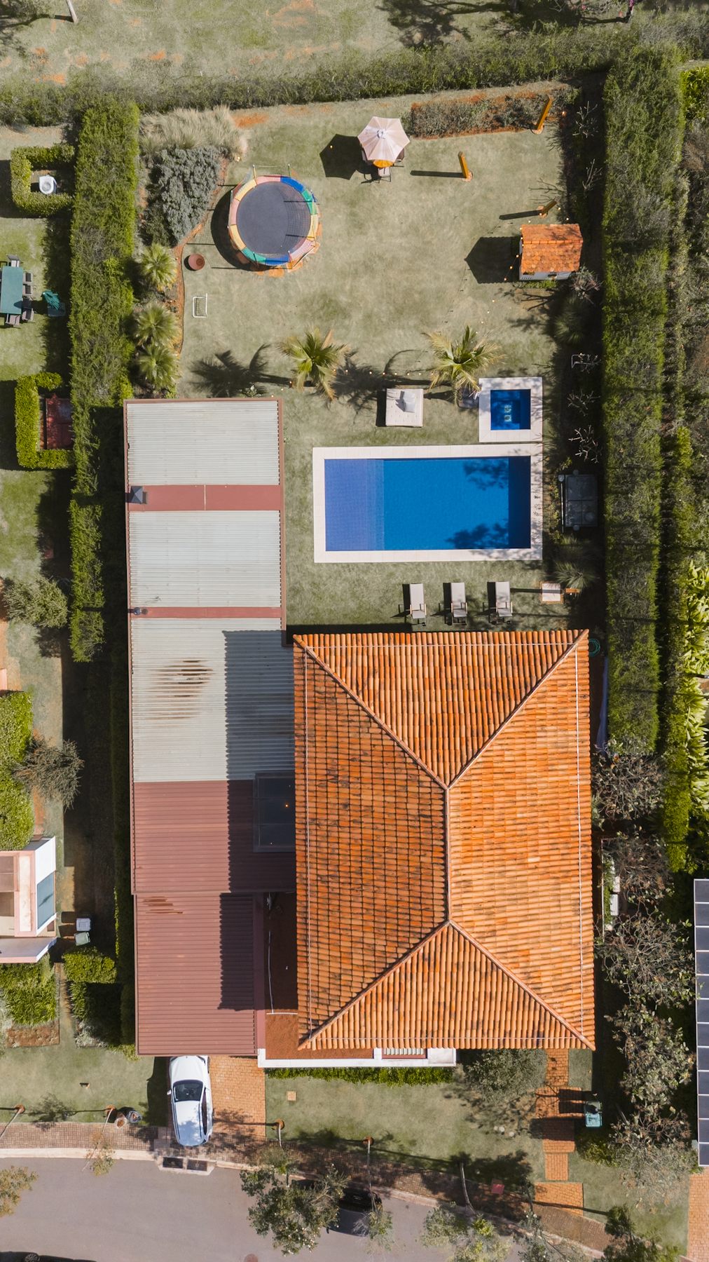 Vista aérea de cima da casa, da piscina e do gramado cercado de vegetação