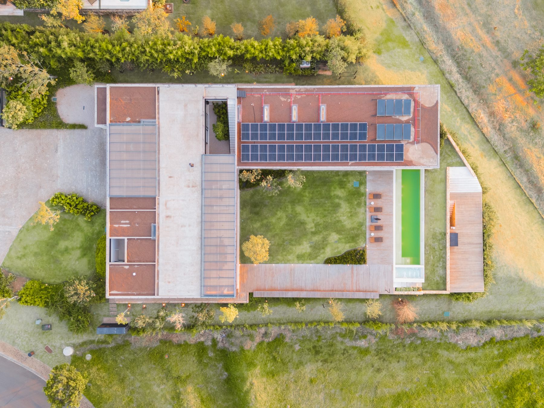 Vista aérea de cima da casa, com o jardim central, a piscina e o telhado com placas solares